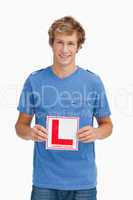 Young blond man holding a learner driver sign