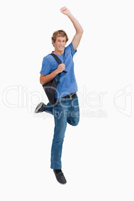 Young blond man jumping with a backpack