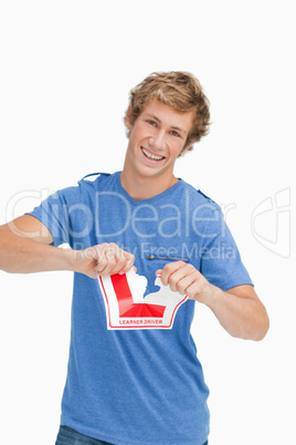 Happy young man ripping a learner driver sign