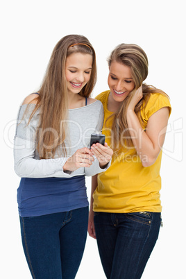 Two females student smiling while looking a cellphone