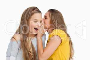 Young woman whispering to her friend