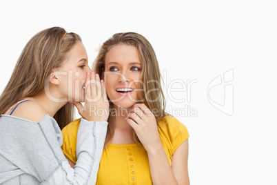 Blonde student whispering to her beautiful friend
