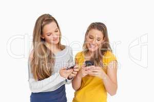 Two young women texting on their cellphones