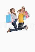 Two young women jumping with shopping bags