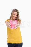 Young blond woman tending a piggy-bank