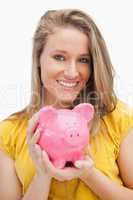 Portrait of a young blond woman holding a piggy-bank