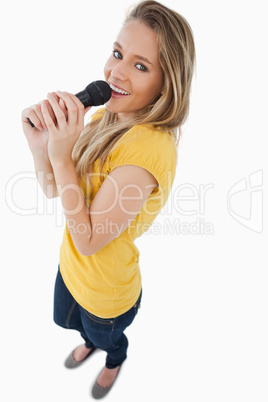 Fisheye view of a blonde girl singing with a microphone