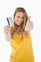 Portrait of a blonde student tending a credit card with the thum