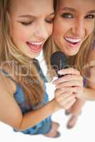 High-angle shot of two happy young blonde singing