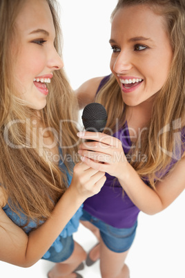 High-angle shot of two happy young beauty singing together