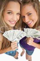 High-angle shot of two happy young beauty holding dollars