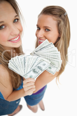 High-angle view of two young woman holding dollars