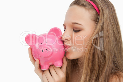 Close-up of a young woman kissing a piggy-bank