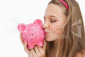 Close-up of a young woman kissing a piggy-bank