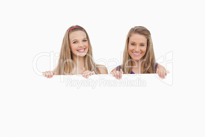 Close-up of two young women holding a blank sign