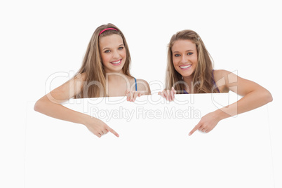 Portrait of young women holding and pointing a blank sign