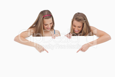 Close-up of young women holding and pointing a blank sign