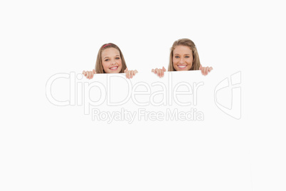 Close-up of young women behind a blank sign