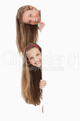 Close-up of two long hair students behind a blank sign