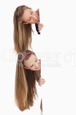 Close-up of two smiling long hair students behind a blank sign