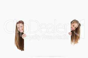 Two long hair women behind a blank sign