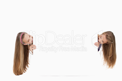 Two long hair young women behind a blank sign