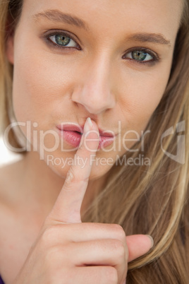 Green-eyes young woman with a finger on the lips