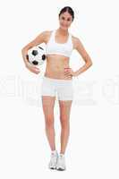 Slim young woman in white clothes holding a soccer ball