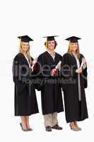 Three smiling students in graduate robe holding a diploma