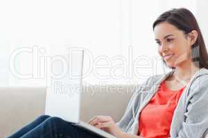 A woman lying on the couch smiling with her laptop