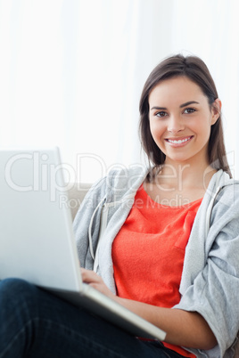 A brightly smiling woman using her laptop