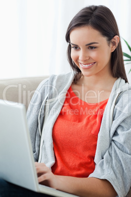 Close up of a woman looking at her laptop while lying on the cou