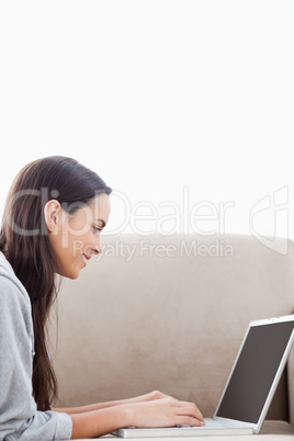 Close up shot of a woman lying on the couch with her laptop