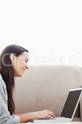 A laughing woman lying on her couch with her laptop