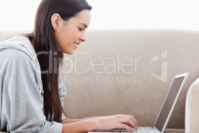 Woman typing on her laptop while lying on the couch