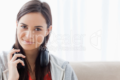 A smirking woman with headphones looks into the camera