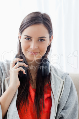 A slightly smiling woman with headphones as she looks into the c