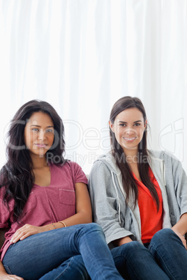 Half length shot of two women on the couch looking into the came