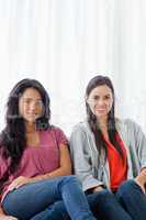 Half length shot of two women on the couch looking into the came