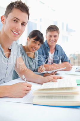 A close up of three studying friends as they look into the camer
