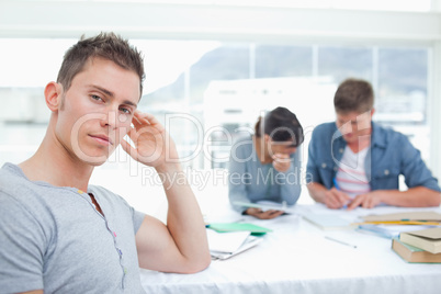 A serious looking student with his hand on his head looks into t