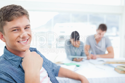 A smiling student with his hand near his chest as he looks into