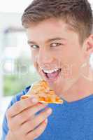 A man with his mouth open about to eat pizza and looking at the