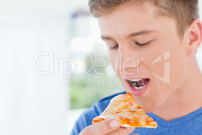 A man with a piece of pizza near his mouth