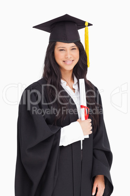 A smiling woman holding her degree as she has graduated from uni
