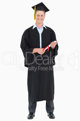 A male graduate with his degree in hand