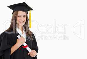 A smiling woman with a degree in hand as she looks at the camera