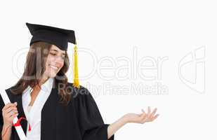 A smiling woman with a degree as she opens out her other hand