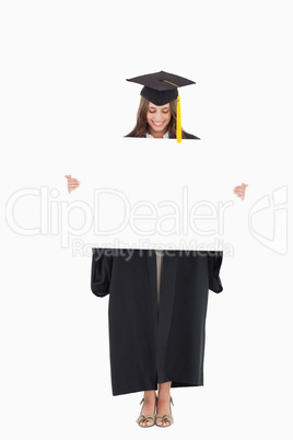 A smiling woman as she holds and looks at a blank sheet in front