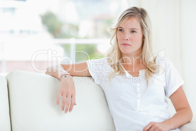 A woman looking to the side as she sits on the couch